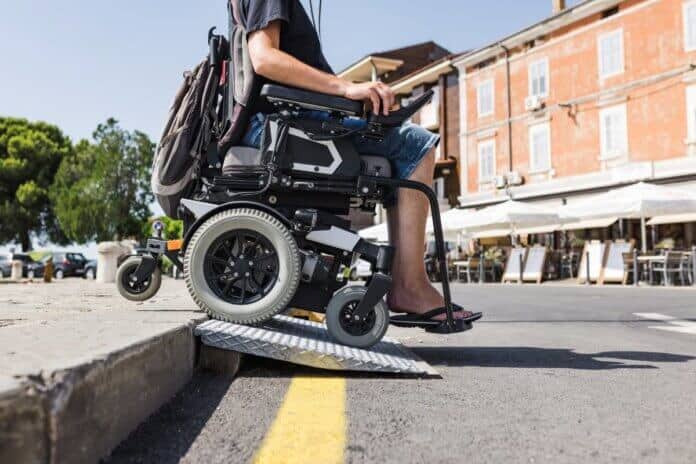 Invalid z električnim vozičkom pelje po klančini.